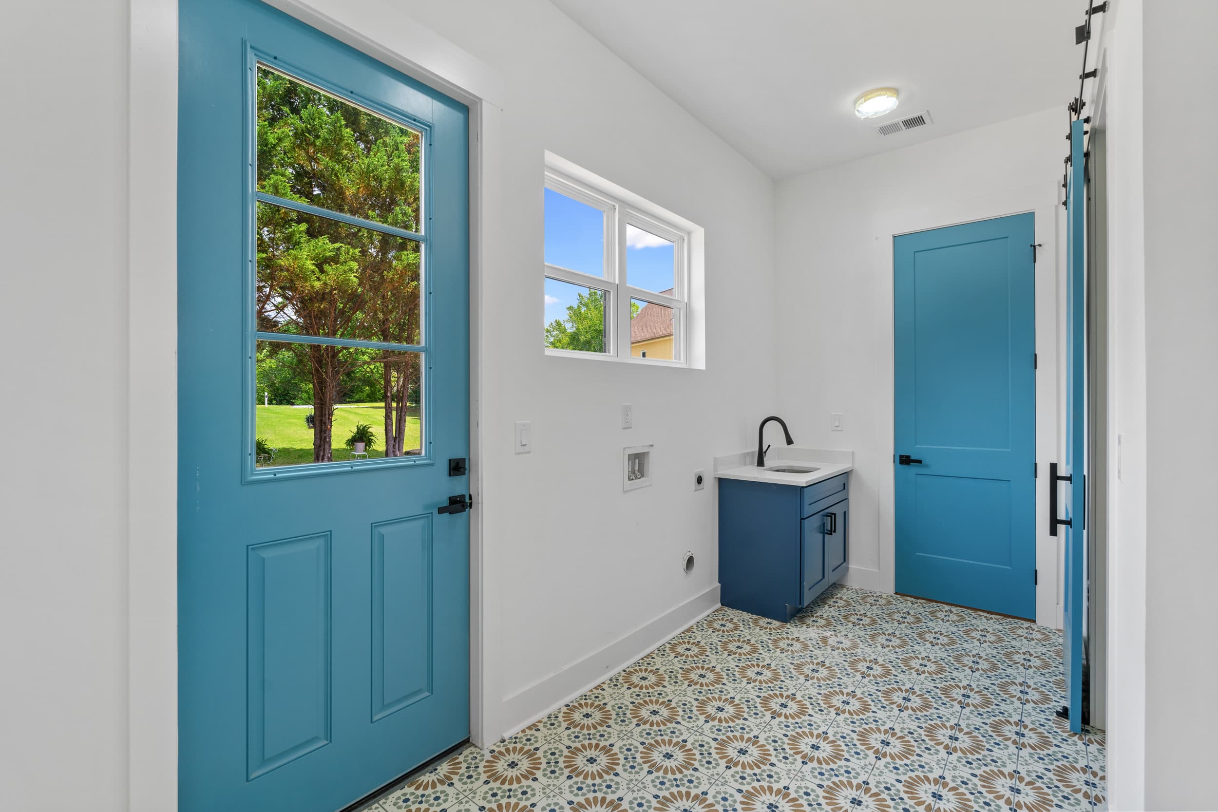 Mudroom with patterned tile and teal cabinetry